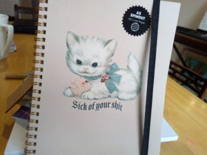A notebook with a kitten on the cover and the words sick of your shit