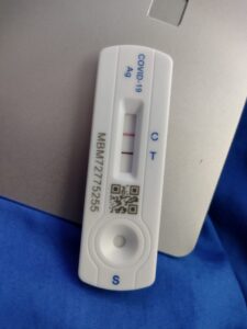 A rapid covid test cartridge showing a positive result